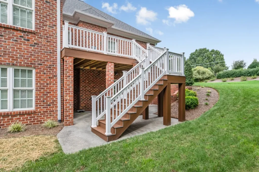 Turnstone Court deck staircase descending to concrete patio beside brick columns and manicured lawn