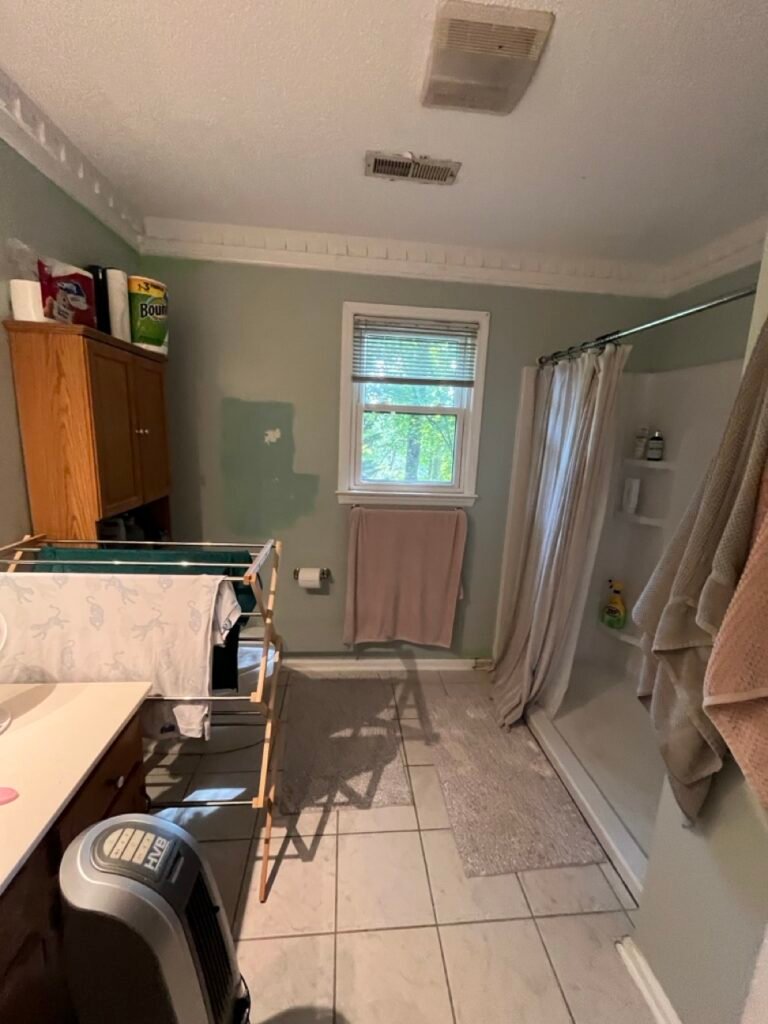 Cramped shower area with fiberglass surround and drying rack before Grinnell Ct bathroom renovation
