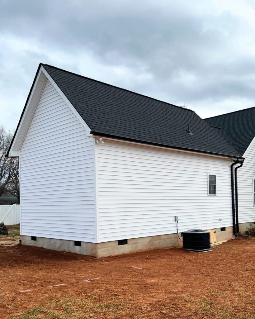 Rear exterior of Lavender Farm Trail in-law suite addition with white siding and black shingle roof
