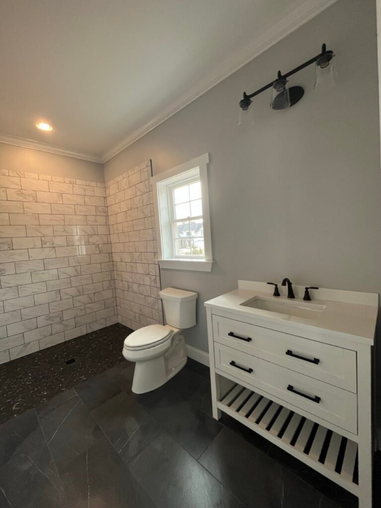 In-law suite bathroom with walk-in tile shower, white shaker vanity and black slate floors
