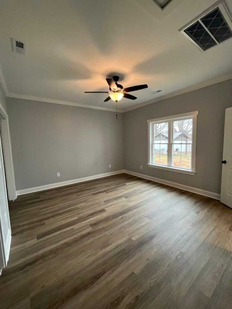 Spacious in-law suite bedroom with ceiling fan, crown molding and wood-look plank flooring