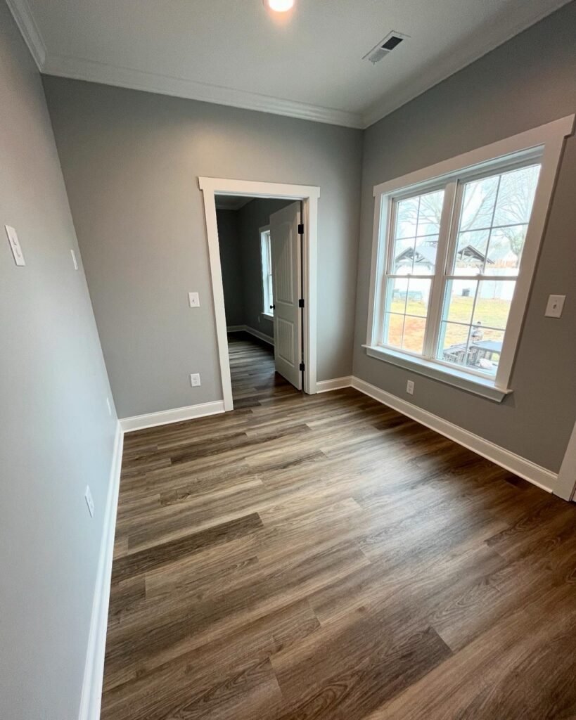 In-law suite bedroom doorway with large double-hung windows and rich plank flooring