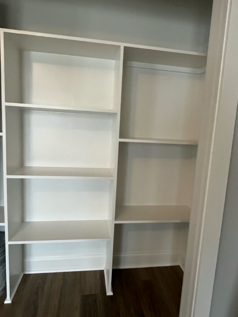 White built-in closet shelving on dark plank flooring inside the Lavender Farm Trail bedroom