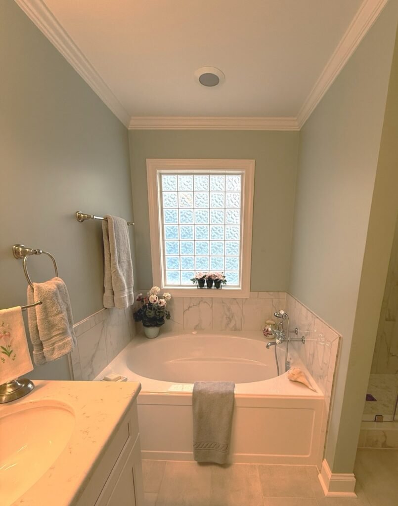 Soaking tub alcove with marble surround and glass block window after remodel