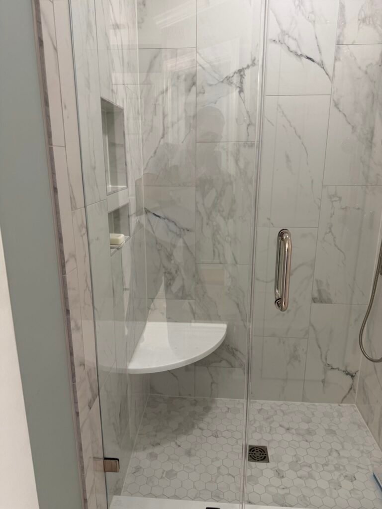 Marble shower interior showing built-in niche corner bench and hexagon mosaic floor