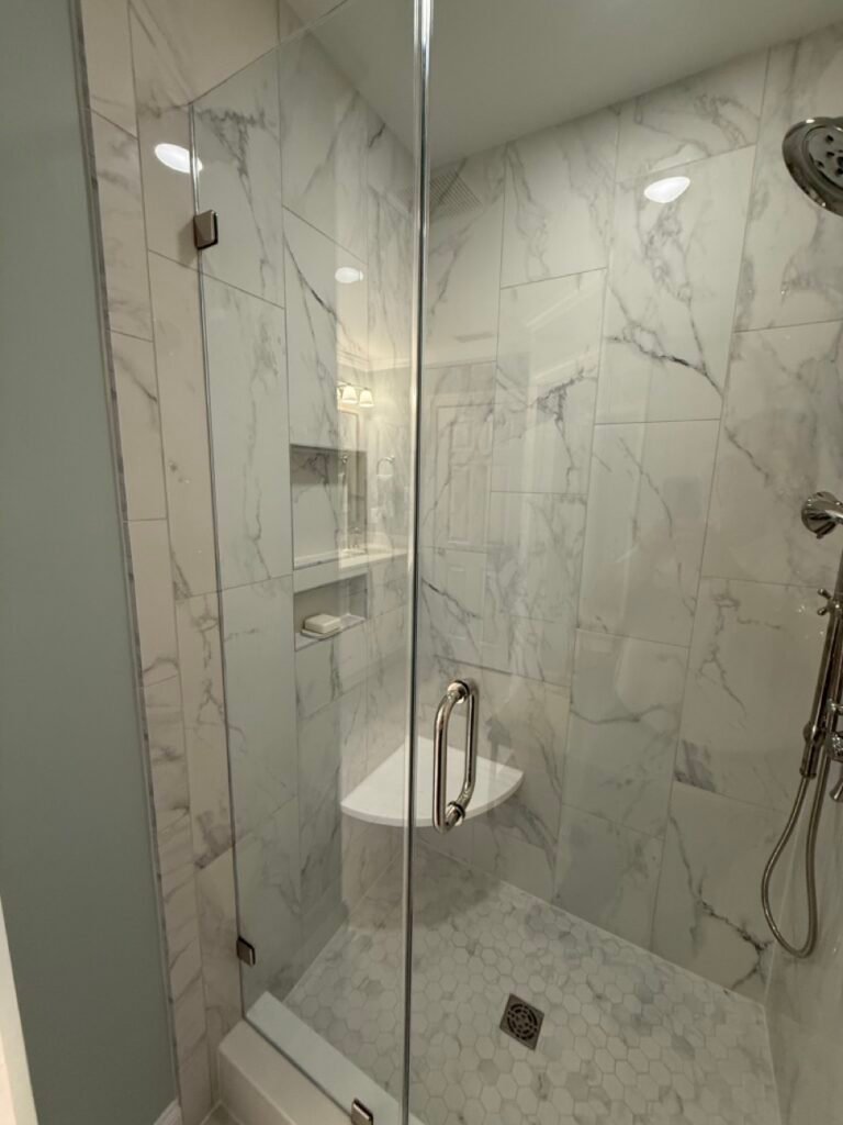 Walk-in shower detail with tiled niche shelving and floating corner seat