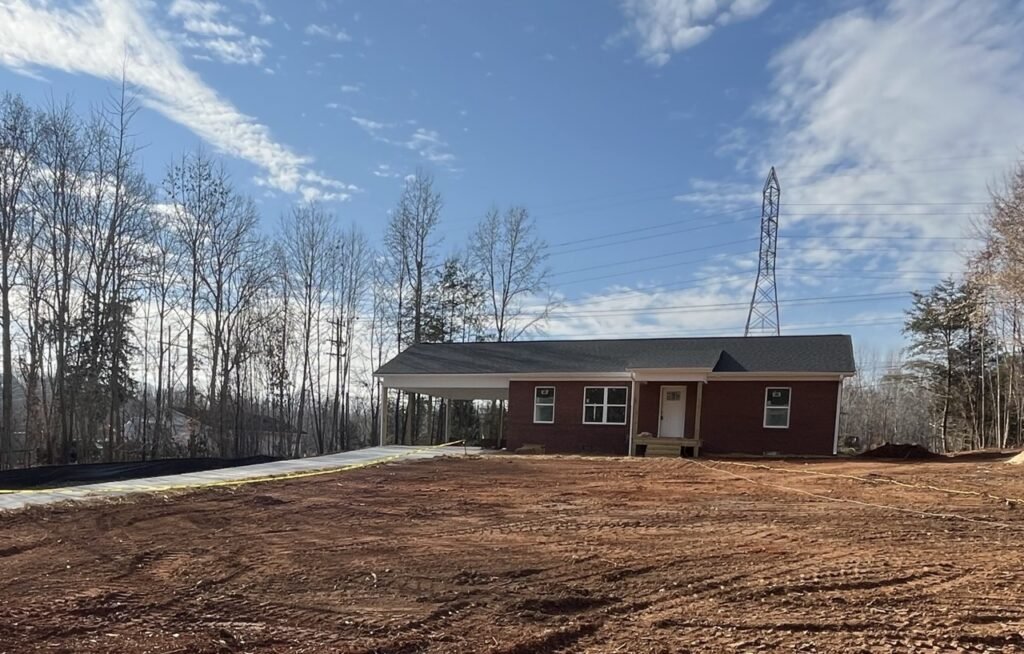 Newly completed brick ranch home with attached carport awaiting move-in day landscaping