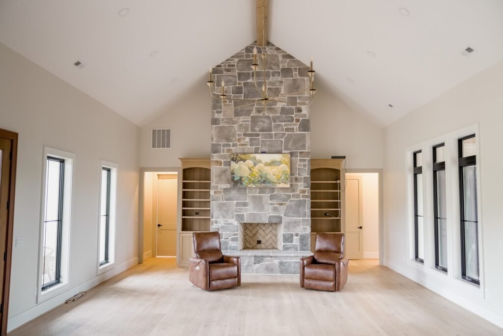 Floor-to-ceiling stone fireplace flanked by built-in shelving in a vaulted great room