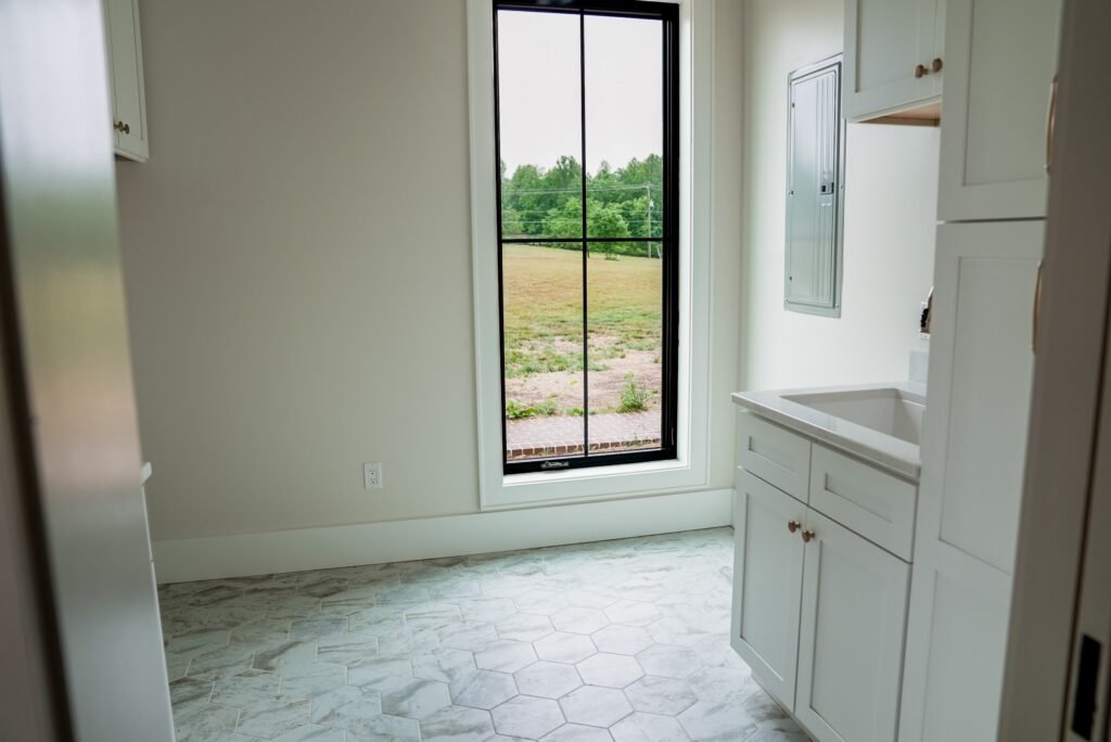 Laundry room with white shaker cabinets, quartz counter and marble hex tile floor