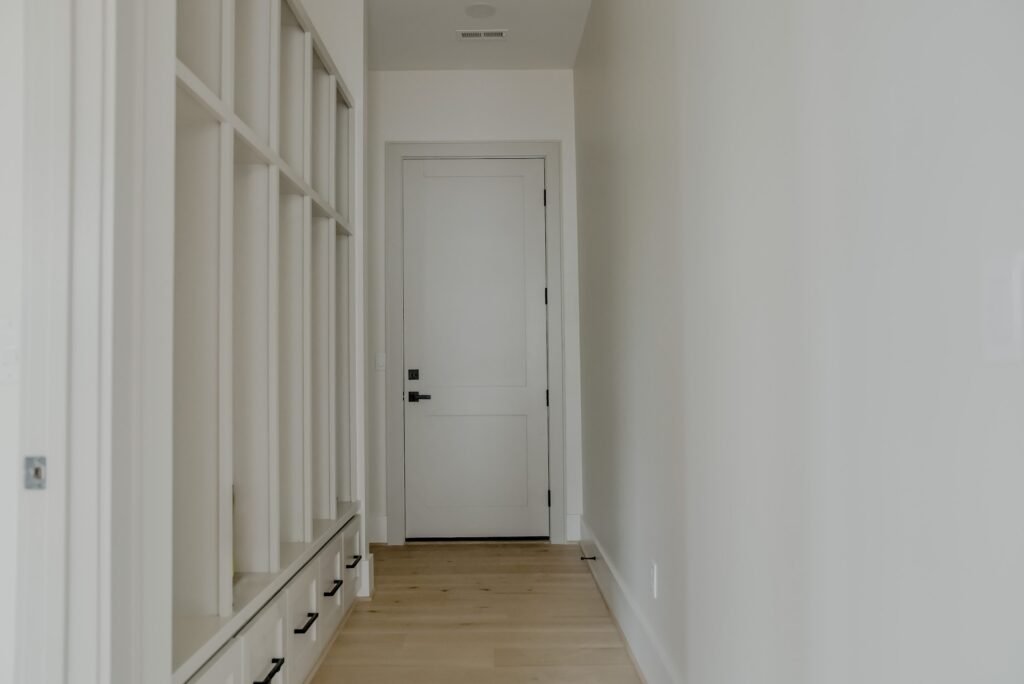 Mudroom hallway with built-in lockers and drawers leading to the rear entry