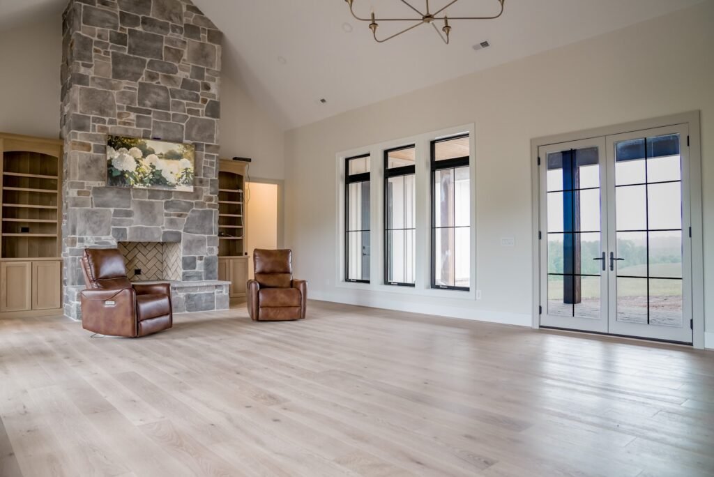 Vaulted great room with a floor-to-ceiling stone fireplace and a wall of windows