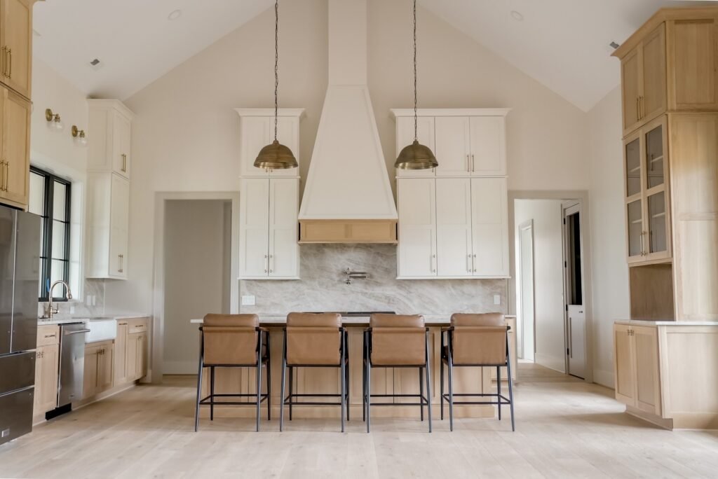 Custom kitchen with a white oak island, plaster range hood and pendant lighting