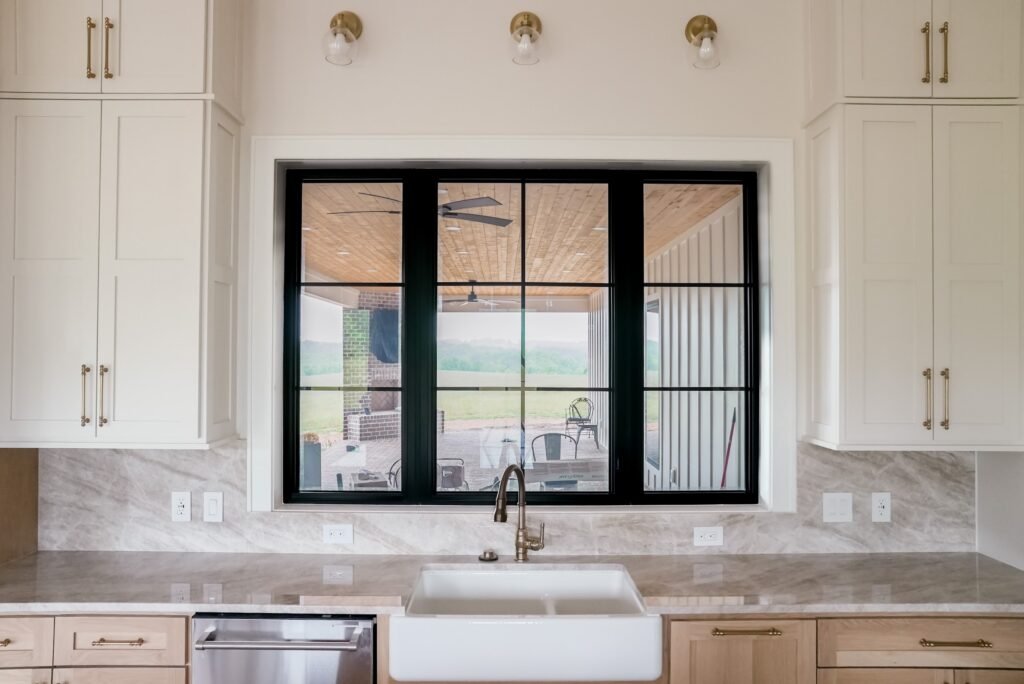 Kitchen with a farmhouse sink, marble counters and a black steel window