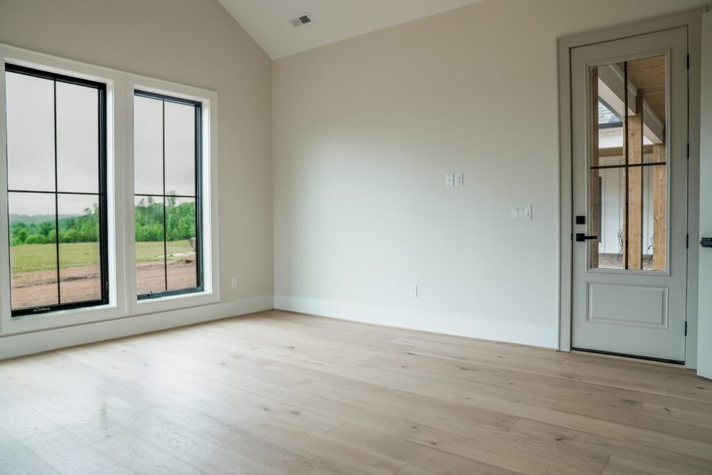 Primary bedroom with a wall of windows and white oak floors