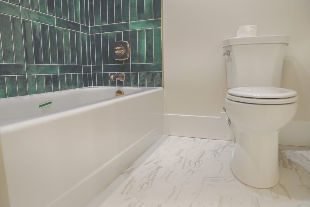 Guest bath with a green tile surround and marble-look floors