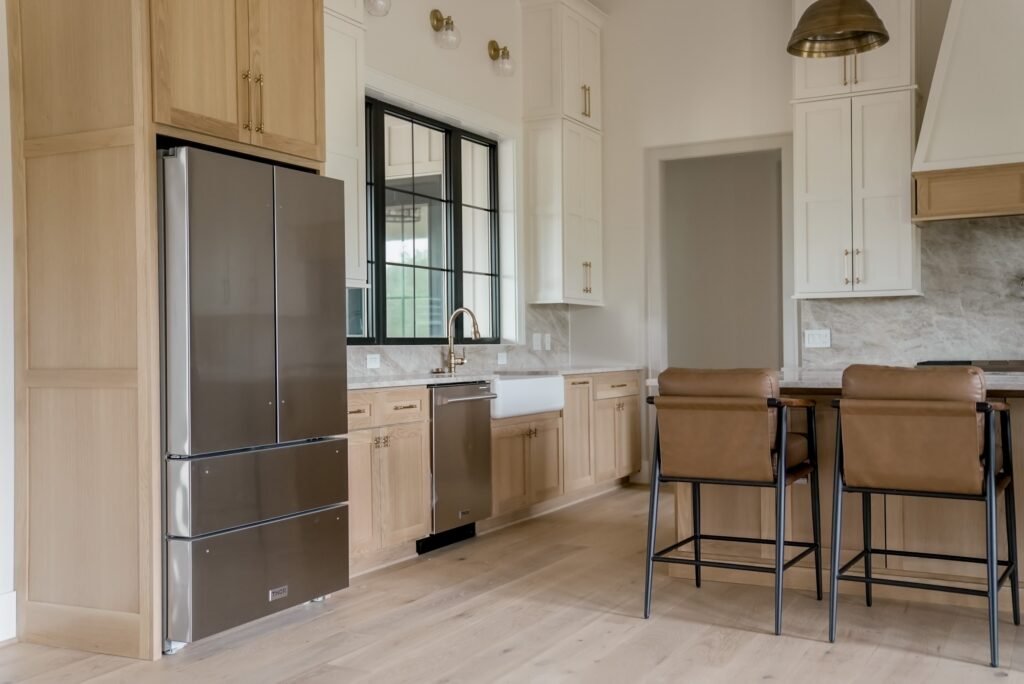 Custom kitchen in the Jack Davis home with marble counters, white oak cabinetry and a plaster range hood