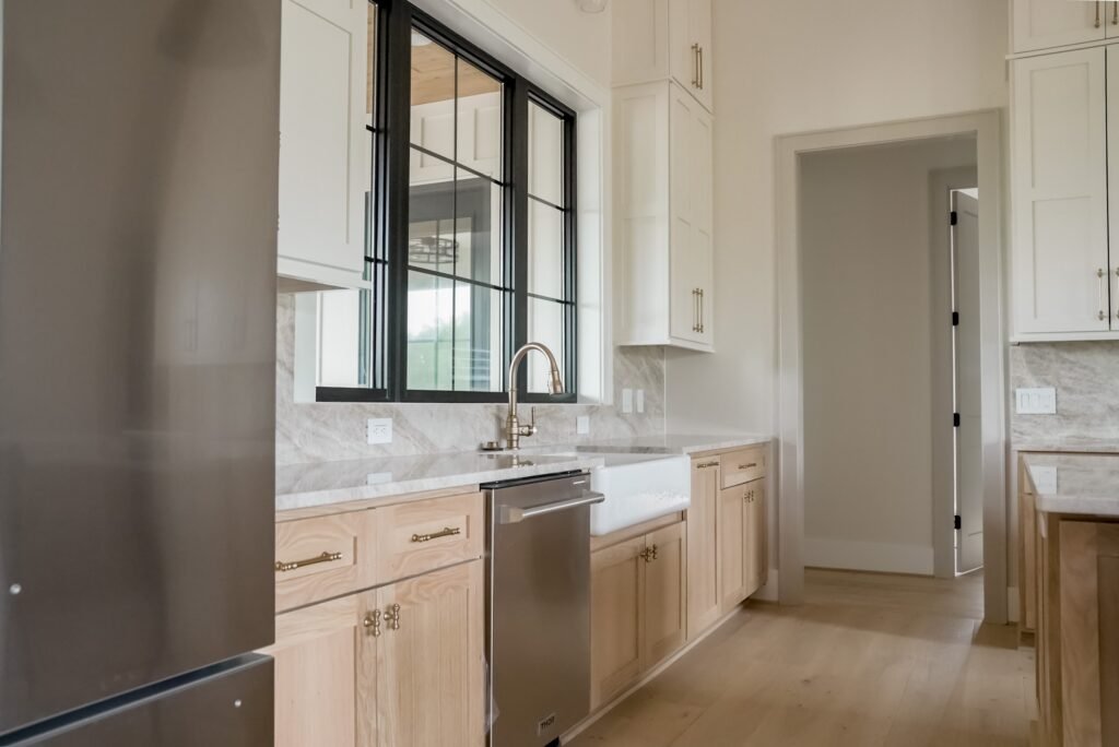 Custom kitchen in the Jack Davis home with marble counters, white oak cabinetry and a plaster range hood