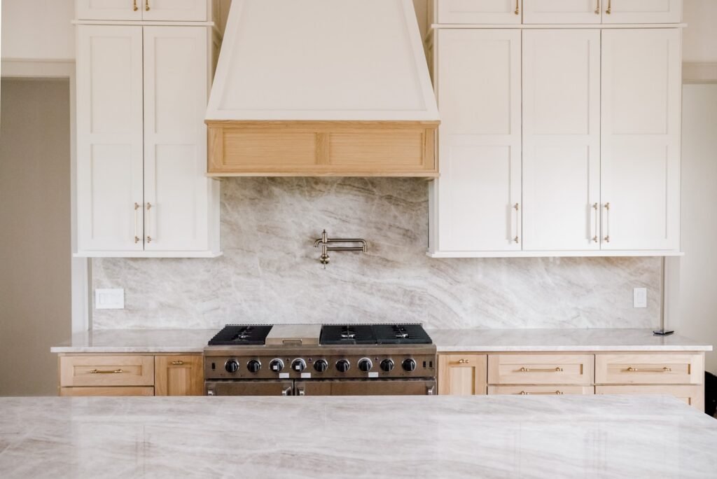 Custom kitchen in the Jack Davis home with marble counters, white oak cabinetry and a plaster range hood