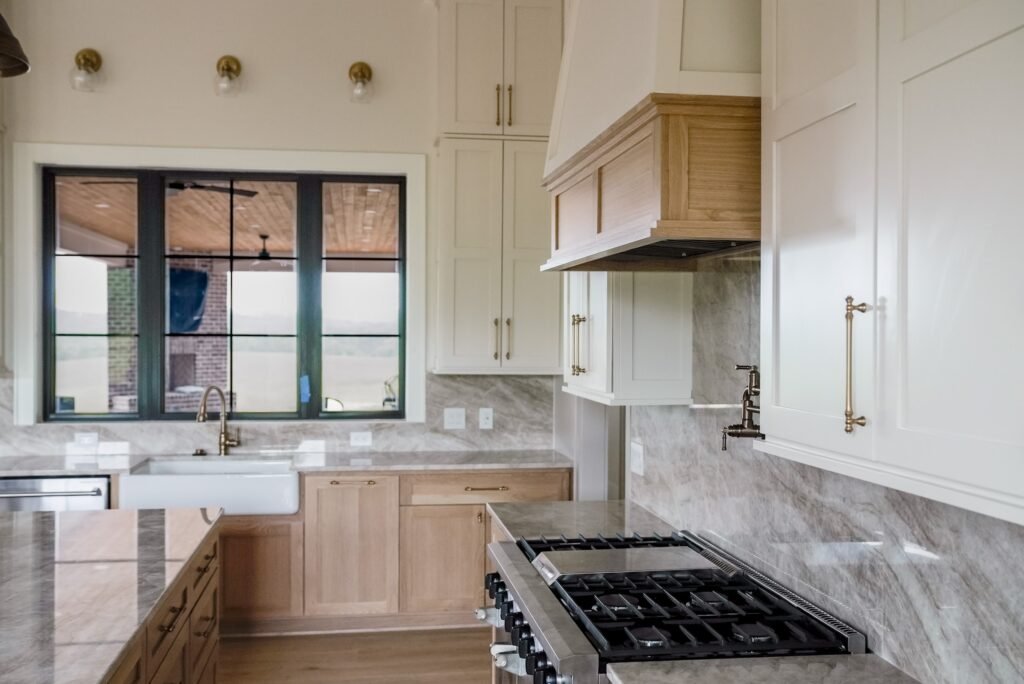 Custom kitchen in the Jack Davis home with marble counters, white oak cabinetry and a plaster range hood