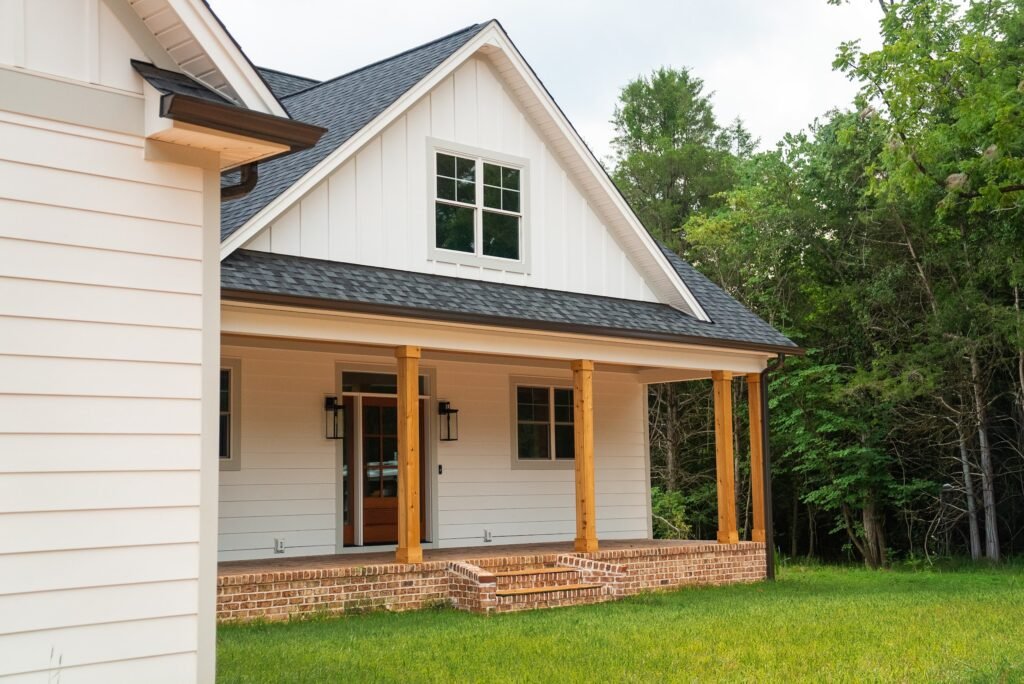 Front exterior of the modern farmhouse with board-and-batten siding, black metal roof and covered porch