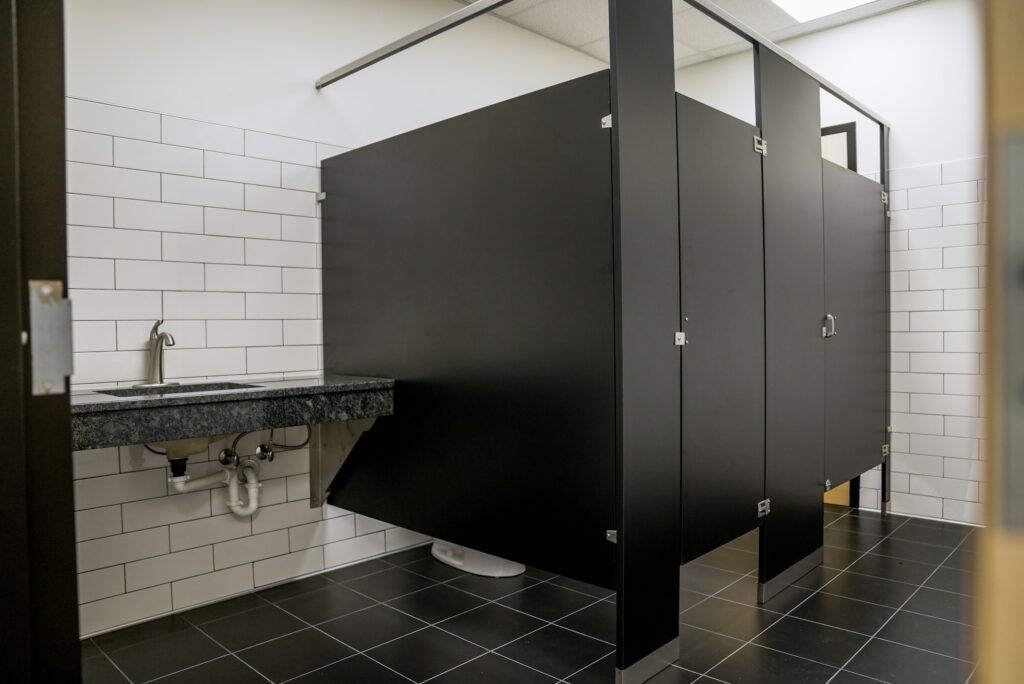 Commercial restroom with tiled walls and partition stalls
