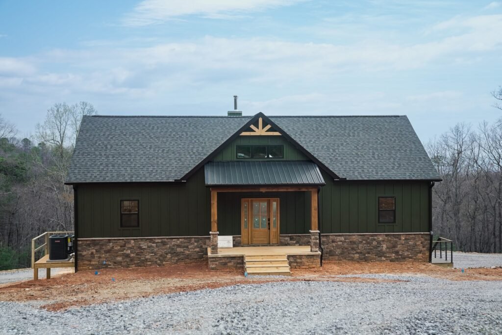 Front exterior of the green board-and-batten custom home with a metal roof and mountain setting